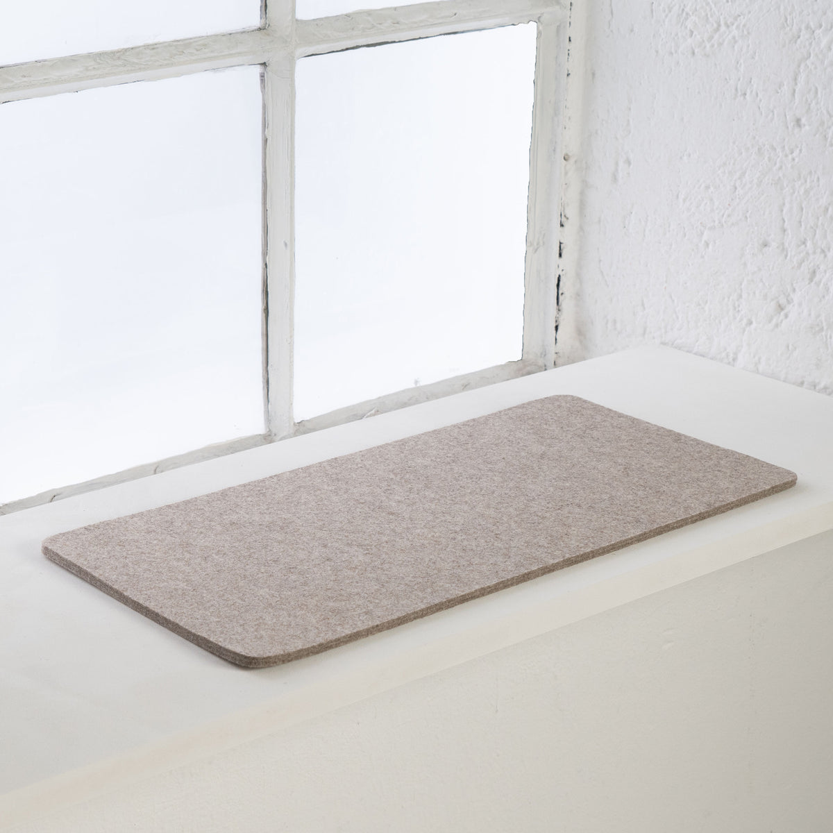 Sandfarbene FELTY Fensterbrettauflage aus Wollfilz auf heller Fensterbank