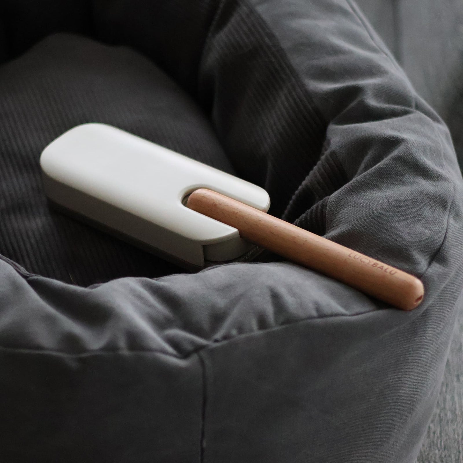 HAIRY Fusselbürste mit Holzgriff liegt in einem grauen Katzenbett
