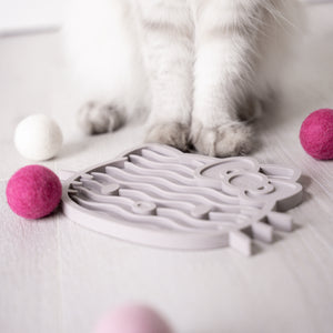 Katze steht vor ZENCAT Schleckmatte - Hello Kitty Edition in Taupe mit Filzbällen