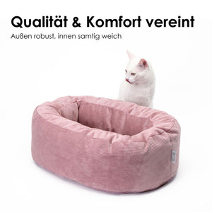 Weiße Katze sitzt neben rosa DINGHY Katzenbett Hello Kitty Edition aus samtigem Cord