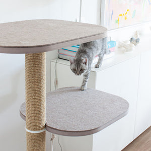 Katze springt vom PEAK Kratzbaum in Weiß mit Filzplattform und Sisalstamm – stylische Kratzmöglichkeit.