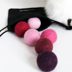 Palline di feltro MAGIC MAGENTA nel sacchetto in tessuto accanto al gatto