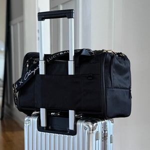 Schwarze CHECK-IN Transporttasche Choupette Edition auf silbernem Rollkoffer befestigt
