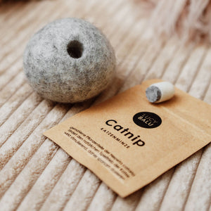 Balle en feutre MINT BALL grise avec ouverture pour l'herbe à chat à côté du sachet d'herbe à chat de LucyBalu