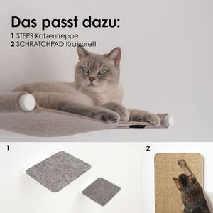 Gatto grigio sdraiato sull'amaca SWING con supporti bianchi – sotto, gli elementi abbinati STEPS per arrampicarsi e la tavola da grattare SCRATCHPAD.