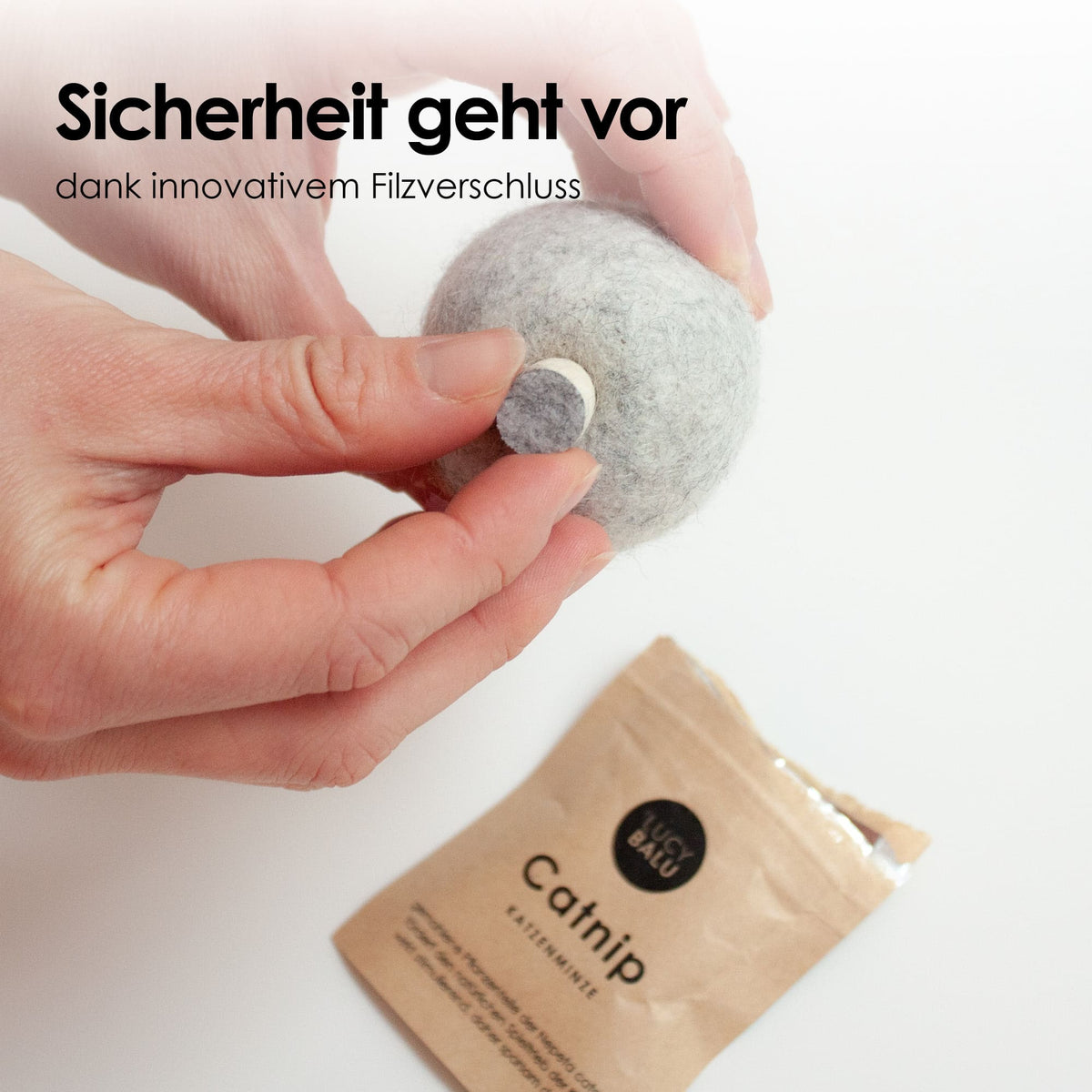 Des mains ouvrant la fermeture innovante en feutre de la balle MINT BALL à côté d'un sachet d'herbe à chat