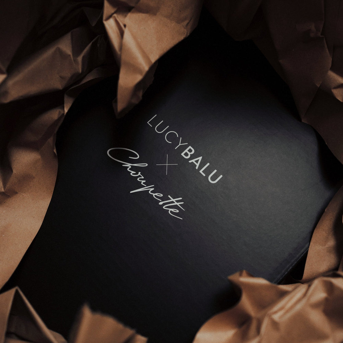 Schwarze Geschenkbox mit geprägtem LucyBalu x Choupette Logo, verpackt in braunem Papier
